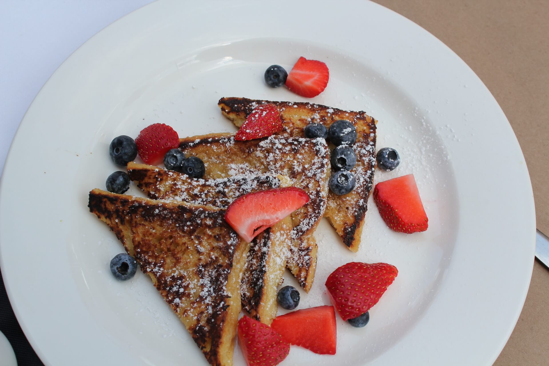 French toast with strawberries and blueberries on a white plate