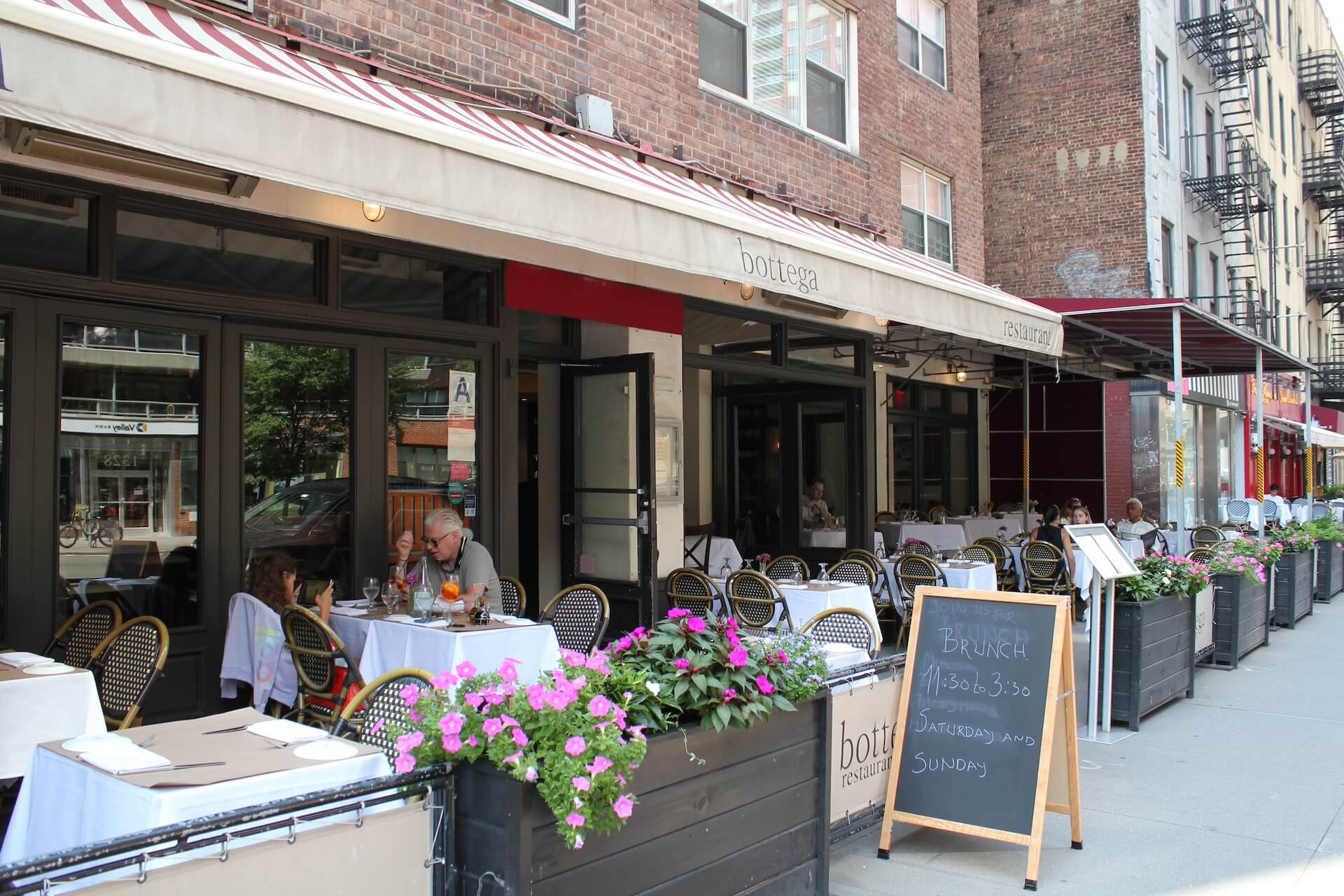 Bottega's sidewalk tables under the striped awning on Second Avenue